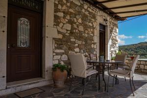 a patio with a table and chairs and a door at Tholos in Áno Dholianá