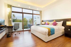 a hotel room with a bed and a desk and a window at Plumeria Maldives in Thinadhoo
