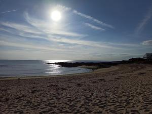 a beach with the sun in the sky and the ocean at Maison de bord de mer - proche plage in La Turballe +1 photo