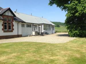 a white building with a large yard in front of it at Siskin Cottage in Lochgilphead