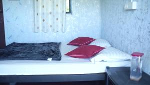 a bed with red and white pillows on it at Wild Tusker Homestay Masinagudi by LexStays in Masinagudi