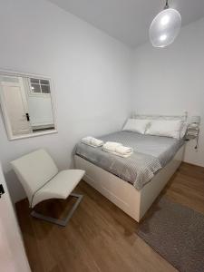 a white bedroom with a bed and a chair at House Pajarillo in Vigo