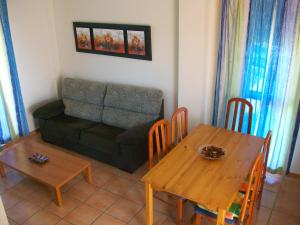sala de estar con sofá, mesa y sillas en APARTAMENTOS PAR TRES - Oliva Nova, en Oliva