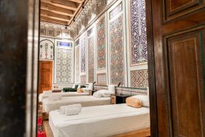 a room with four beds and a wall with tiles at Barlos Noyob Boutique in Bukhara