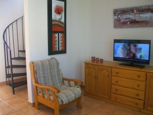 sala de estar con TV en un tocador y una silla en APARTAMENTOS PAR TRES - Oliva Nova, en Oliva