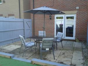 un tavolo e sedie con un ombrellone in un patio di 3 bed house Market Deeping - Peterborough, Stamford, Spalding a Market Deeping