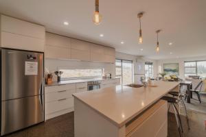 a kitchen with white cabinets and a stainless steel refrigerator at Hillside Haven Perfect Getaway in Lake Tekapo in Lake Tekapo