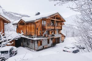 a log cabin in the snow with cars parked in front at Joubarbe Violette by Lodji in Saint-Martin-de-Belleville