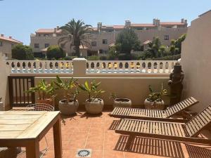 a patio with wooden benches and potted plants on a balcony at Pool House Mencey in El Médano