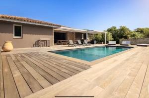 a swimming pool with a wooden deck next to a house at Casa A Sapa in Bonifacio