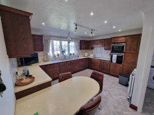 a kitchen with wooden cabinets and a table with chairs at Spacious & Upmarket 2 Bedroom Detached Bungalow in Boston in Boston