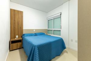 Un dormitorio con una cama azul y una ventana. en Excelente ubicación a 200m de la playa de Bombinhas, en Bombinhas