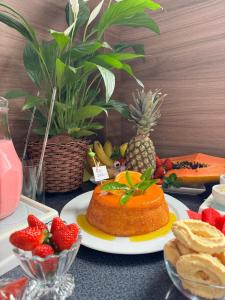 Una mesa con un pastel y fresas y una piña. en Hotel LENA, en São Luís Gonzaga