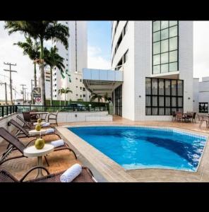 a swimming pool with lounge chairs and a building at Hotel Natal Plaza com piscina, academia, 100m da praia de Ponta Neg in Natal