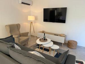a living room with a couch and a table and a tv at Maison indépendante 2 Chambres avec terrasse et jardin in Saint-Aunès