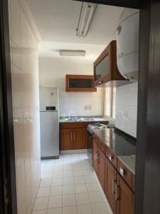a kitchen with a white refrigerator and wooden cabinets at Panorama Al Shorouk apartment with view in Madīnat ash Shurūq