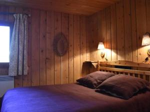 una camera da letto con pareti in legno e un letto con due cuscini di Chalet typique 8 personnes à Méribel, calme et pittoresque - FR-1-180-190 a Méribel
