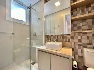 a bathroom with a sink and a glass shower at Apartamento de Última Geração em Atlântida in Xangri-lá