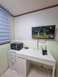 a room with a desk with a tv on the wall at king's house in Gwangju