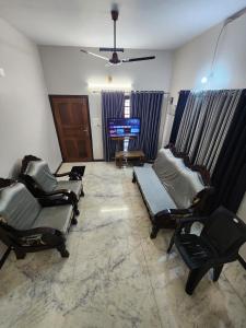 a living room with three chairs and a television at Budget Home in Cochin