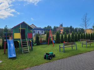 a park with a playground with a slide and benches at Hibiskus - domki letniskowe in Jastrzębia Góra