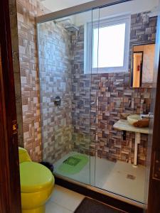 a bathroom with a glass shower with a yellow toilet at Hotel Salty House in Uyuni