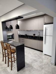 Il comprend une cuisine équipée d'un comptoir noir et d'un réfrigérateur blanc. dans l'établissement Amplo apartamento na quadra mar, à Balneário Camboriú 12 autres photos