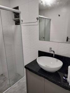 une salle de bain avec un lavabo et une douche en verre dans l'établissement Amplo apartamento na quadra mar, à Balneário Camboriú