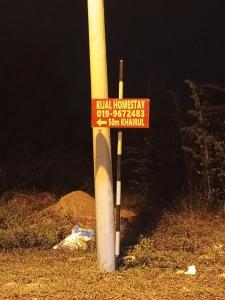 a street sign on a pole in the grass at Kijal Homestay in Kemasik