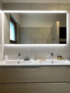 une salle de bain avec deux lavabos et un grand miroir dans l'établissement Rustic Apartment -200mt from BerninaExpress, à Tirano