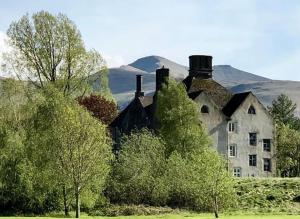 an old house with mountains in the background at Cosy Welsh Town Cottage in Brecon