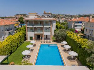 a swimming pool with chairs and umbrellas in front of a building at Çilek Marina Otel in Çeşme
