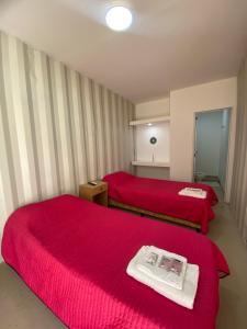 Un dormitorio con dos camas con sábanas rojas y una revista encima. en Hotel en Ruta, en Fiambala 13 fotos más