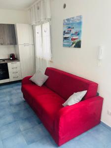 a red couch sitting in a living room at Licinio's Apartments - Casa Lavanda in Pantelleria +16 photos