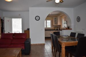 ein Wohnzimmer und eine Küche mit einem Tisch und einem roten Sofa in der Unterkunft Casa Inmaculada con piscina privada in Cómpeta