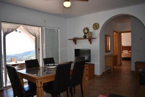 ein Esszimmer mit Tisch und Stühlen und einem Fernseher in der Unterkunft Casa Inmaculada con piscina privada in Cómpeta