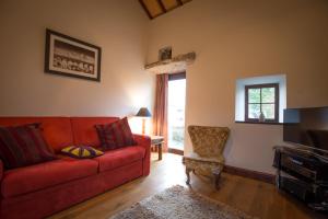a living room with a red couch and a chair at Hen Gamdda Fawr in Llanallgo