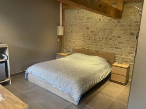 a bedroom with a bed and a brick wall at Chambre à la campagne la ch tite bauquerie in Commes