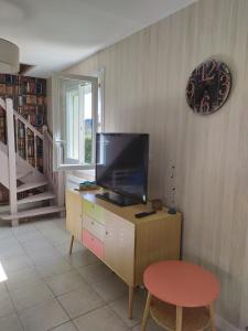 een woonkamer met een televisie op een dressoir met een kruk bij Maison de vacances à Portsall in Portsall