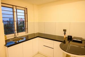 una piccola cucina con un lavandino e una finestra di Manhas Olympus a Ernakulam