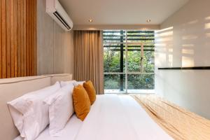 麦德林Spot Building的卧室里有一张白色的大床，上面放着橙色的枕头