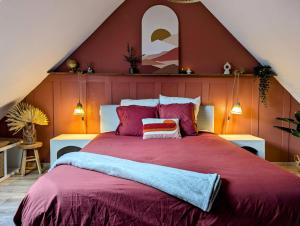 a bedroom with a large bed with a red comforter at Le Petit Bali in Sélestat