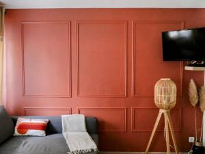a living room with a red wall with a couch at Le Petit Bali in Sélestat