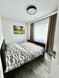 a bedroom with a bed with a comforter and a window at Kaštonų krantas in Antotylʼtse
