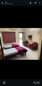 a large bedroom with two beds and a television at Golden Glory Guest House in Hyderabad