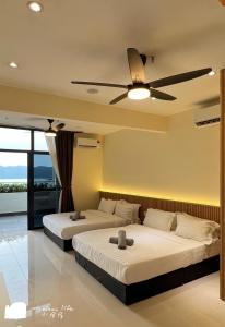 two beds in a room with a ceiling fan at The Shore Maison Life 小居屋 in Kota Kinabalu