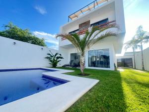 a white house with a swimming pool and a palm tree at Casa VillaTeques alberca jacuzzi in Tequesquitengo