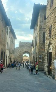 Un grupo de personas caminando por un callejón con un puente. en Il Vecchio Convento, en San Gimignano