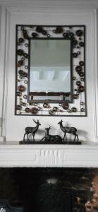 a mirror above a fireplace with two deer statues on it at LA GAUDINIERE in Lyons-la-Forêt