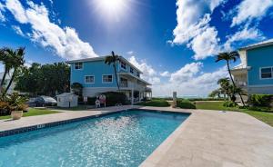 a house and a swimming pool in front of a house at 7Mile Beachfront Apartment in George Town
